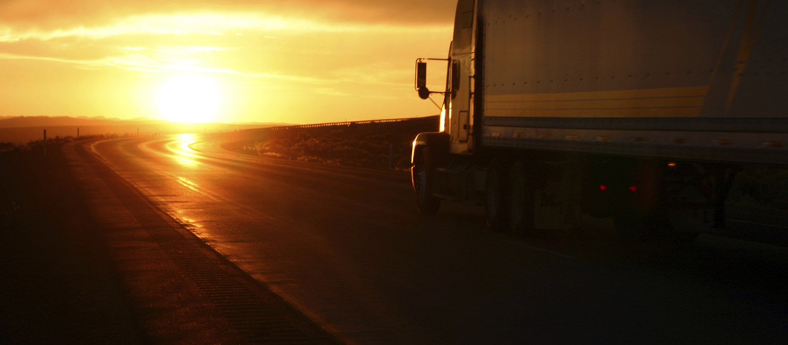 Tractor trailer driving into sunset